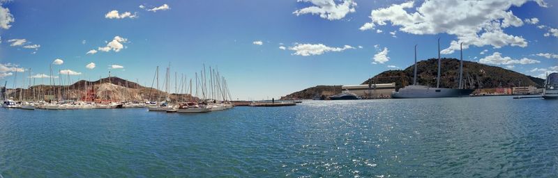 Sailboats moored in sea against sky