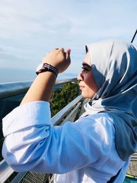 Portrait of young woman wearing sunglasses standing against sky