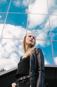 Low angle view of young woman standing against sky