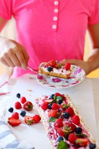 High angle view of woman holding strawberry on table