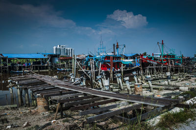 Fishing boats moored at wooden jetty against sky