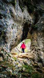 Woman standing through a whole in a rock