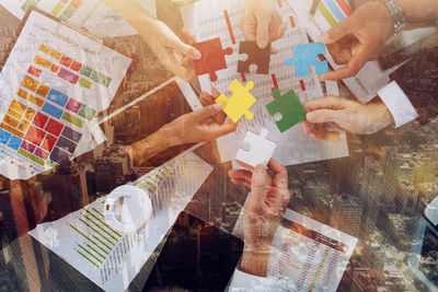 Cropped hand of woman holding jigsaw puzzle on table