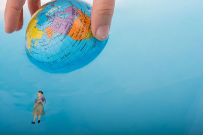 Cropped hand holding globe in swimming pool