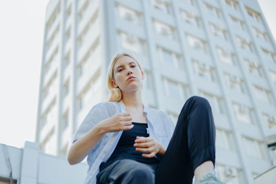Low angle view of young woman standing against building