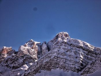 Snowcapped rocky mountain against clear sky