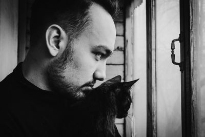 Man with cat looking through window