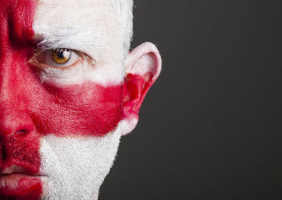 Close-up portrait of man with english flag body paint against black background