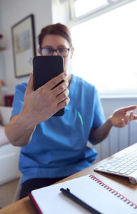 Midsection of man using mobile phone while sitting on table