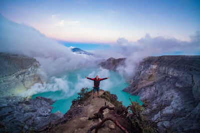 Man standing on rock against sky