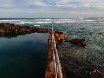 Scenic view of sea and rockpool against sky