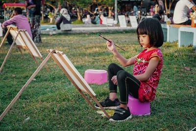 Side view of cute girl painting in park