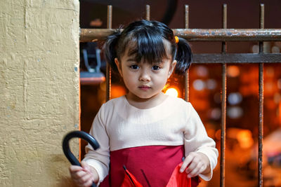 Portrait of girl standing by railing at night