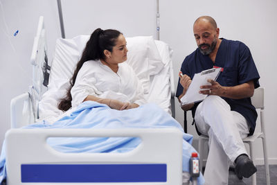 Female patient on hospital bed talking to nurse