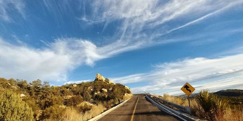 Road amidst trees against blue sky