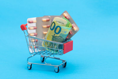 Close-up of shopping cart against blue background