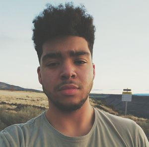 Portrait of young man standing against sky