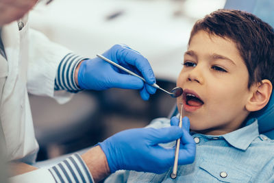 Cropped image of dentist examining boy at clinic