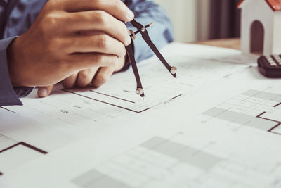 Midsection of man working on blueprint