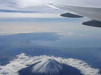 Aerial view of aircraft wing over landscape against sky