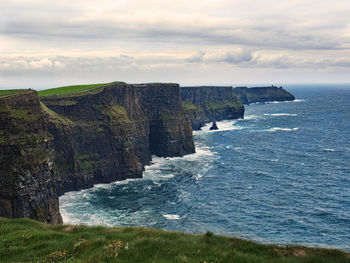 Scenic view of sea by cliff against sky