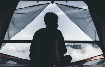 Rear view of silhouette man sitting in tent