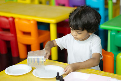 Boy holding dropper while painting toy