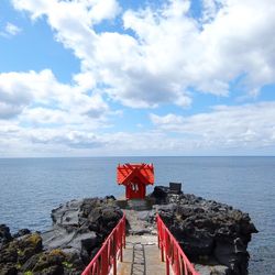 Footbridge on rock formation in sea against sky