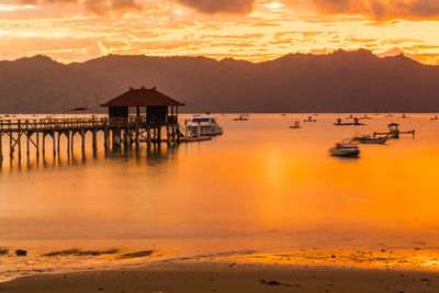 A wooden pier stretches out into a calm bay at sunset, near trenggalek, east java, indonesia.