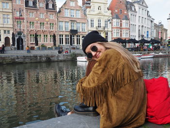 Woman with umbrella in canal in city