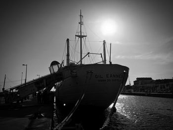 Sailboats moored at harbor against sky