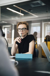 Businesswoman discussing with transgender colleague over laptop in board room during meeting