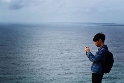 Young woman standing in sea against sky