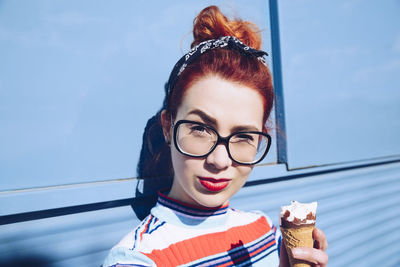 Portrait of redhead young woman holding ice cream cone against mini van