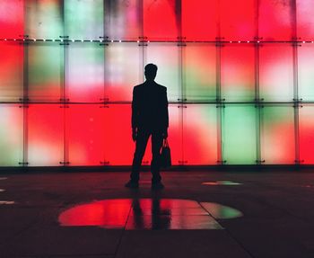 Full length rear view of silhouette man walking in illuminated building