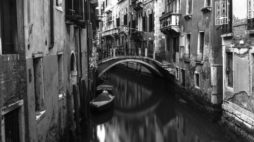 Reflection of man standing on canal in city