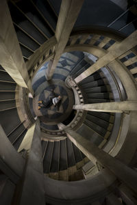 Directly above view of woman lying by spiral staircase in building