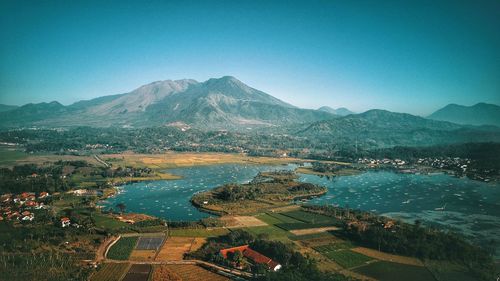 Aerial view of lake and mountains against clear blue sky