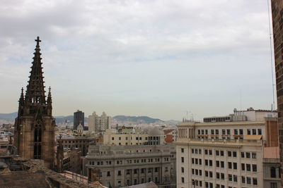 Buildings in city against cloudy sky