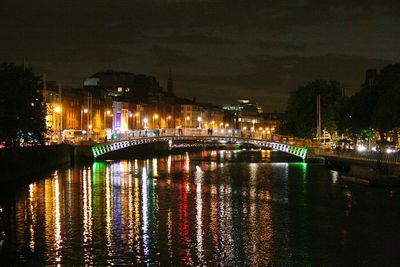 Illuminated bridge over river against sky at night