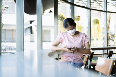 Side view of young man using mobile phone while sitting at home