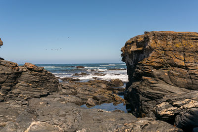 Rock formation on beach against clear blue sky