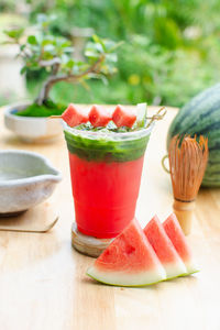 Matcha with watermelon juice in the glass on wooden table.