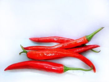 Close-up of red chili peppers over white background