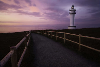 Pathway by lighthouse against sky during sunset