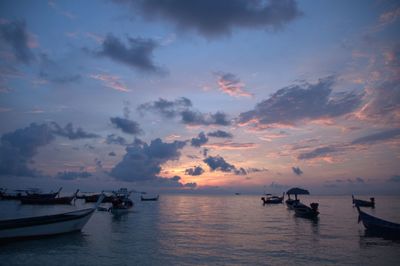 Boats moored in lake against sky during sunset