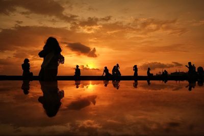 Silhouette people standing against sky during sunset