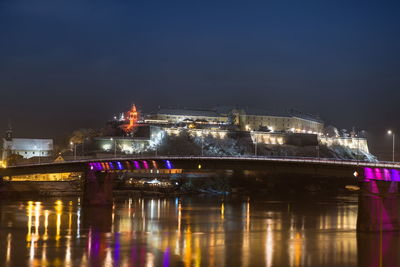 Illuminated bridge over river at night