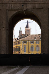 Buildings against sky seen through arch window