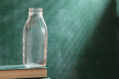 Close-up of glass bottle on book against green background